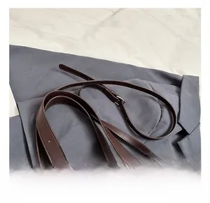 Detail of brown matte tote bag with silver buckle and chocolate-shaped pendant charm