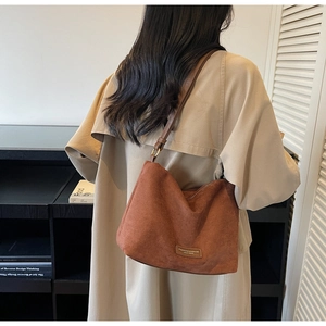 Détail d'un sac cabas en daim marron avec bandoulière et trench-coat élégant