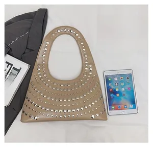 Khakifarbene Tasche mit Nieten im Größenvergleich mit einem iPad und Büchern