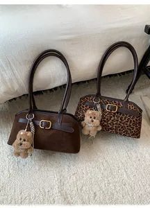Dettaglio di borse sottobraccio leopardate e in pelle scamosciata con ciondoli morbidi