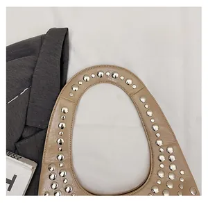 Detail der schicken beige Schultertasche mit silbernen Nieten und glattem Griff
