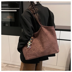 Detailansicht der Wildleder-Tote mit goldenen Nieten und farbenfrohem Fransenanhänger