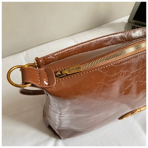 Macro detail of brown waxed leather tote bag showing gold metal zipper and texture