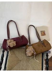Close-up of retro suede shoulder bags in burgundy and khaki with cute teddy bear charms