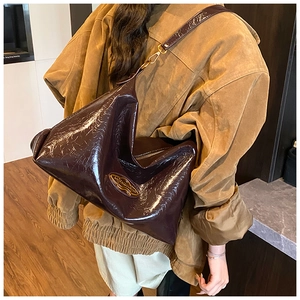 Detail of dark brown glossy large tote bag showing soft pleated texture and metal logo