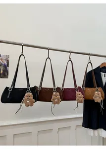Suede baguette bags in four colors with teddy bear charms on metal display racks