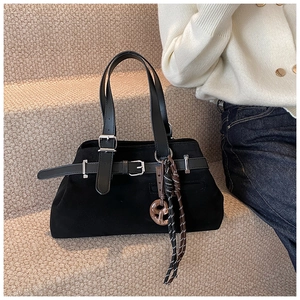 Detail of vintage matte black tote bag showing metal buckle strap and woven pendant charm