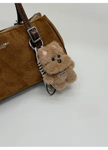 Detailed close-up of brown plush puppy bag charm with engraved bone-shaped metal tag