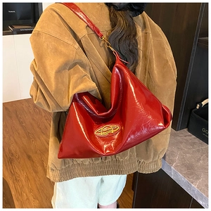 Close-up of red patent leather tote bag with glossy texture and golden logo detail