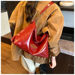 Macro view of glossy red patent leather texture and gold brand logo on the tote bag
