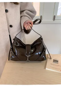 Detail of dark brown glossy leather hobo bag featuring adjustable strap and silver metal clasp