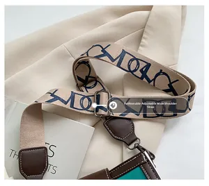 Detail of adjustable wide fabric shoulder strap with blue letter print and brown leather