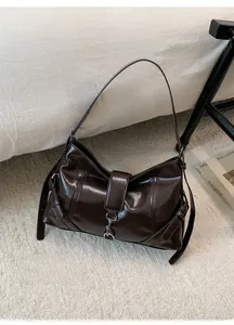 Detail of glossy dark brown leather shoulder bag with silver buckle and side strap design