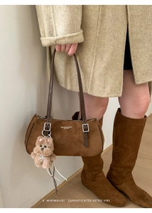Detail of brown suede baguette bag with leather strap and a cute teddy bear charm