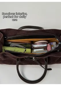 Vue intérieure du grand sac cabas en daim marron foncé rempli d'objets du quotidien