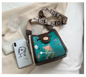 Close-up of vintage green crossbody bag with bear graffiti and wide floral strap