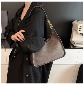 Detail of dark brown woven tote bag with gold chain and soft suede matte texture
