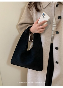 Detailed view of the soft suede texture and minimalist tailoring on the black tote bag