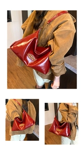 Detailed macro view of glossy burgundy patent leather tote bag with gold oval logo