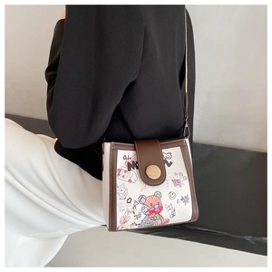 Detail of crossbody bucket bag featuring colorful bear graffiti and wood-textured clasp