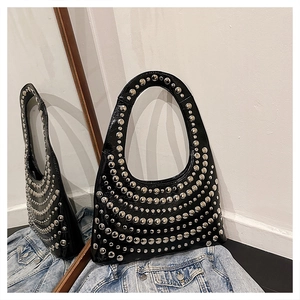 Nahaufnahme der schwarzen glänzenden Hobo-Tasche mit silbernen Nieten auf Denim-Stoff