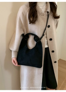 Detail of the unique knot handle and matte texture on this black minimalist shoulder bag