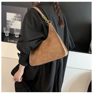 Detail of a dark brown suede shoulder bag with geometric shape and thick stitch trim