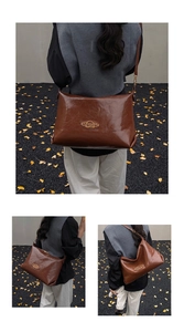 Detail of caramel brown wax leather shoulder bag with vintage gold logo and long strap