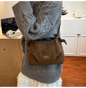 Detail of vintage brown matte hobo bag with contrast stitching and shoulder knot accent