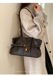 Nahaufnahme der braunen Retro-Tote-Bag mit Ziergürtel und goldenem Herzanhänger