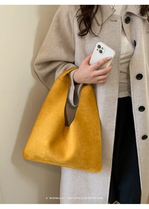 Close-up of minimalist mustard yellow suede shoulder bag with retro geometric texture