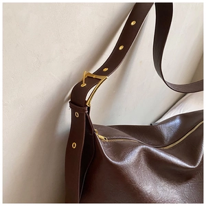 Detail of dark brown leather tote showing fine grain texture and gold metal eyelets