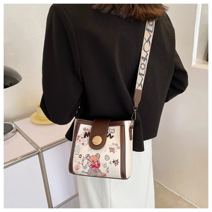 Close-up of white crossbody bag featuring cartoon bear graffiti and a wide canvas strap