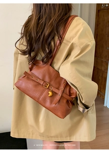 Detail der braunen Retro-Tasche mit goldenem Herzanhänger und Schnallenriemen-Dekor