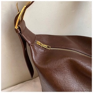 Detailed macro view of the smooth golden zipper and premium brown leather texture of the bag