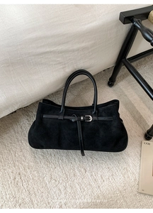 Detail of a vintage black suede tote bag with silver buckle on a textured rug
