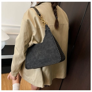 Detail of black matte shoulder bag with golden chain strap and contrast stitching details