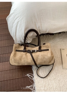 Close-up of minimalist brown suede tote bag with leather straps on a white carpet