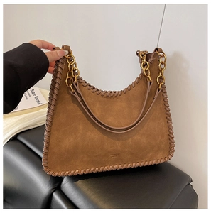 Detail of brown suede shoulder bag with whipstitch edges and thick gold chain strap