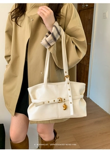 Detail der weißen Retro-Einkaufstasche mit goldenem Herzanhänger und Lederschnalle