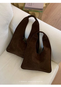 Detail of dark brown suede tote bags in two sizes on a soft white sofa setting