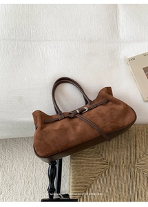 Detailed texture of brown frosted leather tote bag with dark leather straps on a woven stool