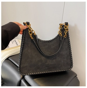 Detail of black suede shoulder bag with thick leather woven edges and gold chain straps