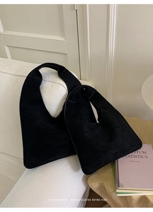 Detail of two minimalist black suede hobo bags in different sizes on a white sofa