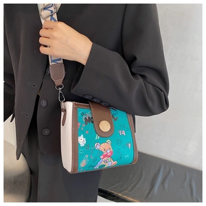 Detail of blue graffiti crossbody bag with bear print and wide woven shoulder strap
