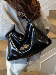 Glossy black large tote bag with gold logo plate and shoulder strap for daily commuting