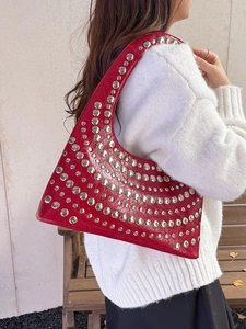 Rote Hobo-Tasche mit Krokodil-Muster und Nieten, getragen von einem Model im Freien