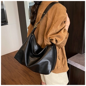 Detail of black pebbled leather hobo bag with adjustable strap and gold metal buckle