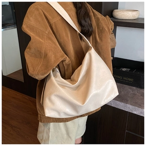 Detail view of the soft beige leather tote bag showing its texture and wide shoulder strap