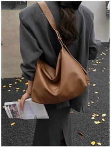 Detail of soft brown leather tote bag with gold buckle hardware and wide shoulder strap
